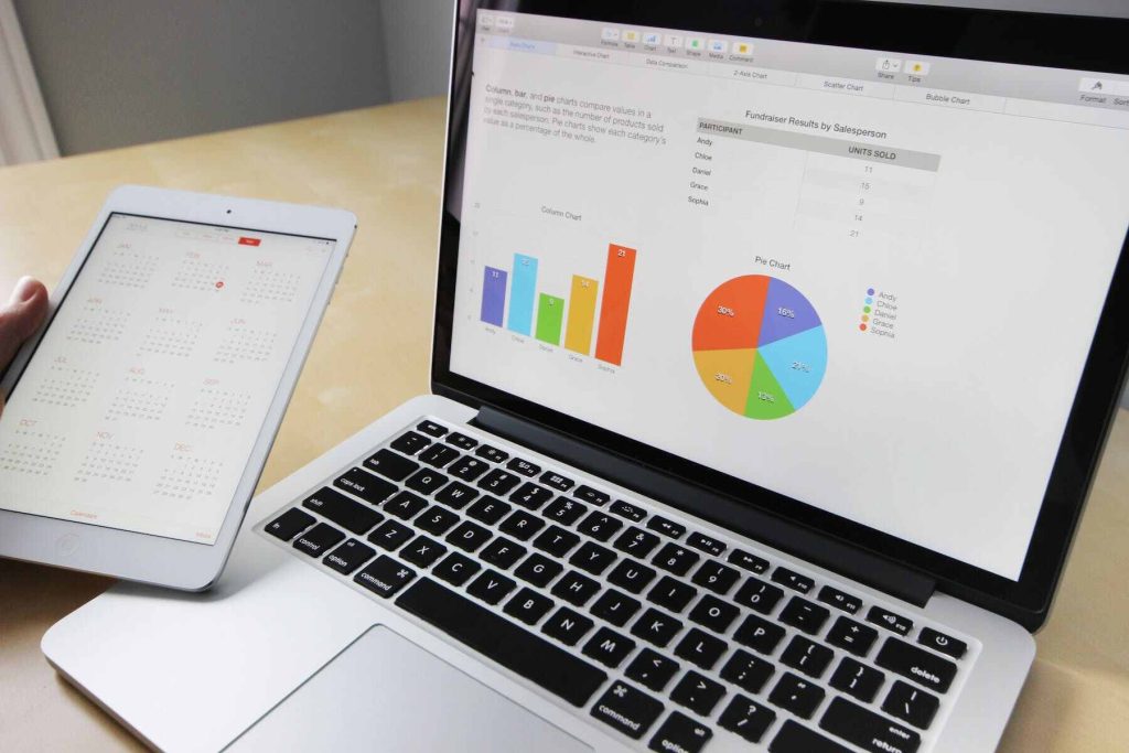 An image of a laptop with some charts and a tablet viewing a calendar