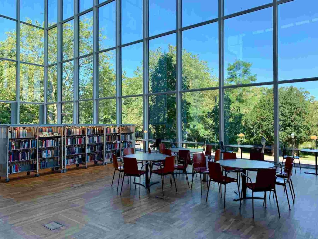 An image of a library with books in the shelves with tables and chairs