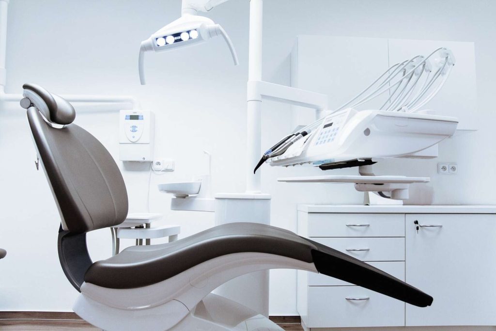 A dental chair, lighting, and some dentist tools