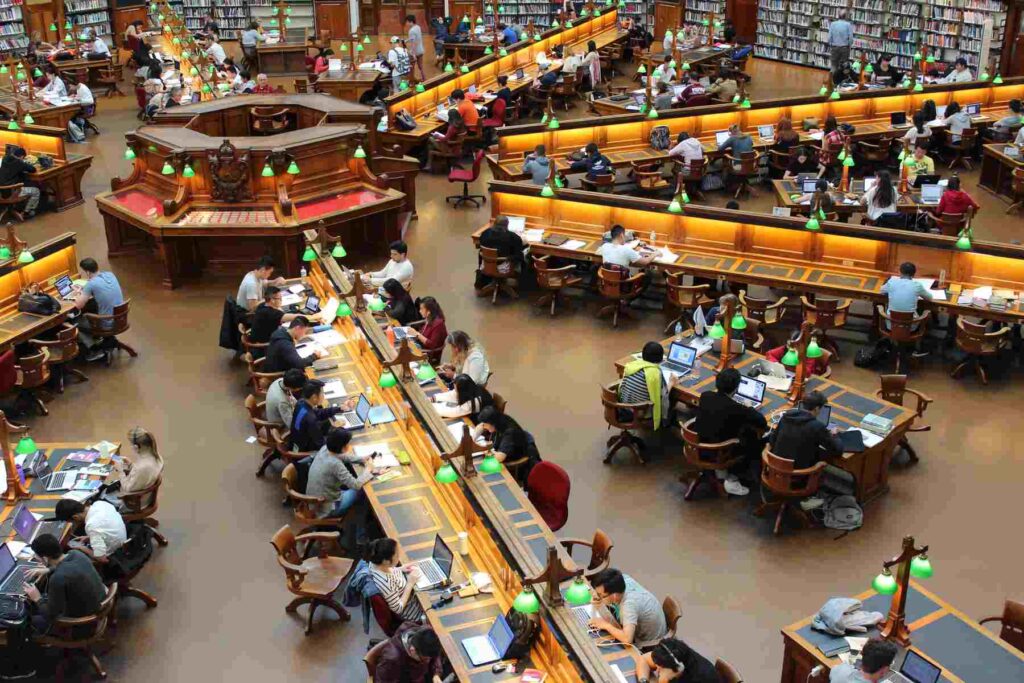 A library of a big university full of students studying on the table